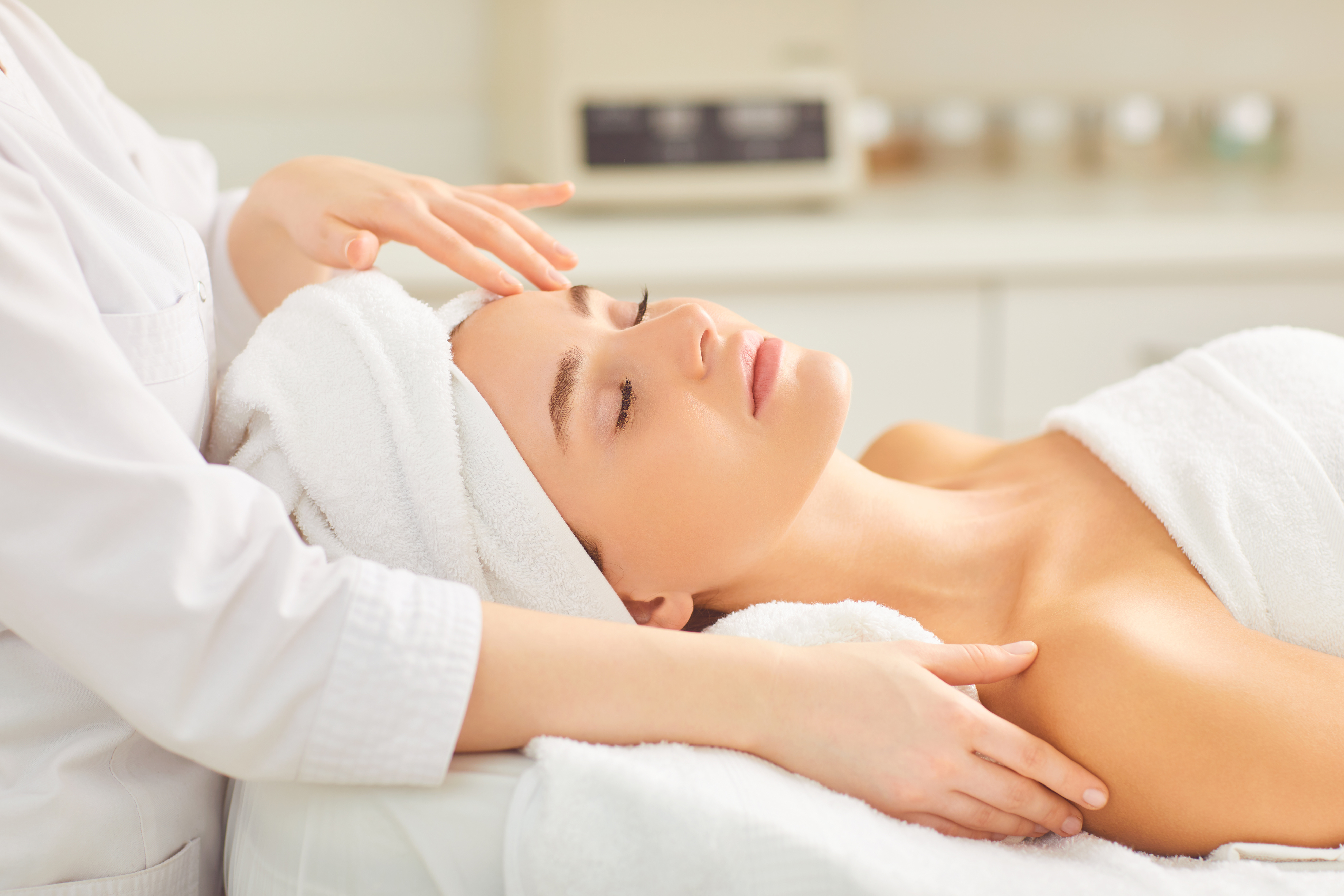 Facial Massage for a Young Woman Lying in a Beauty Salon.